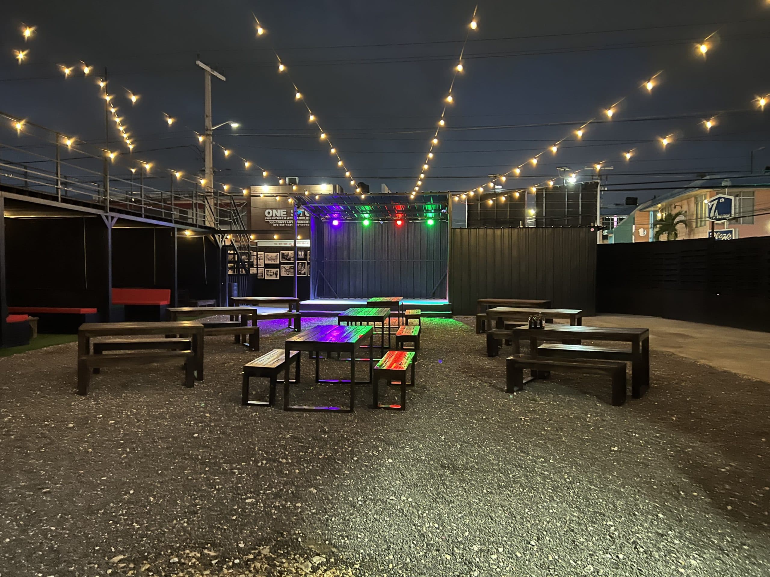 Di Lot at Plantation Smokehouse Kingston — string lights, stage and picnic seating